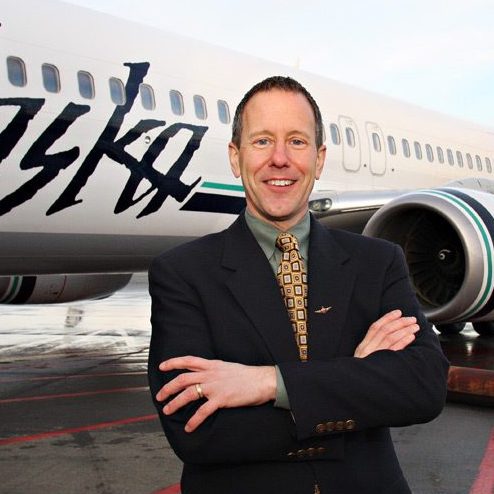 Man in suit in front of airplane