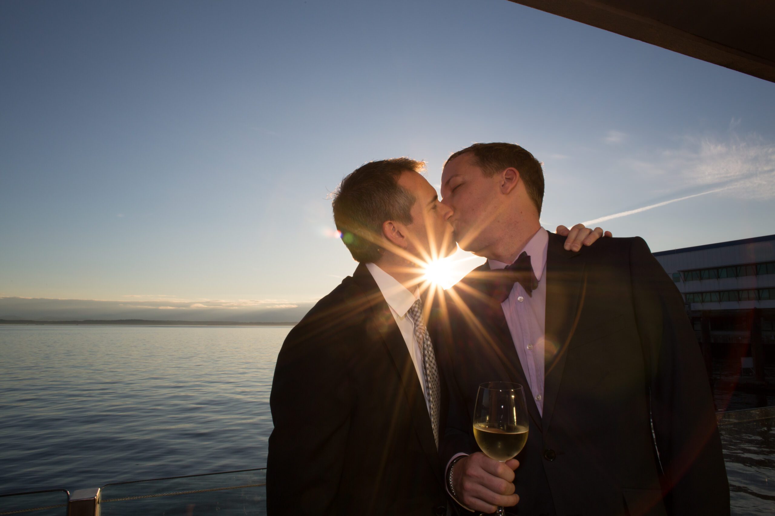 Two men kissing at sunset